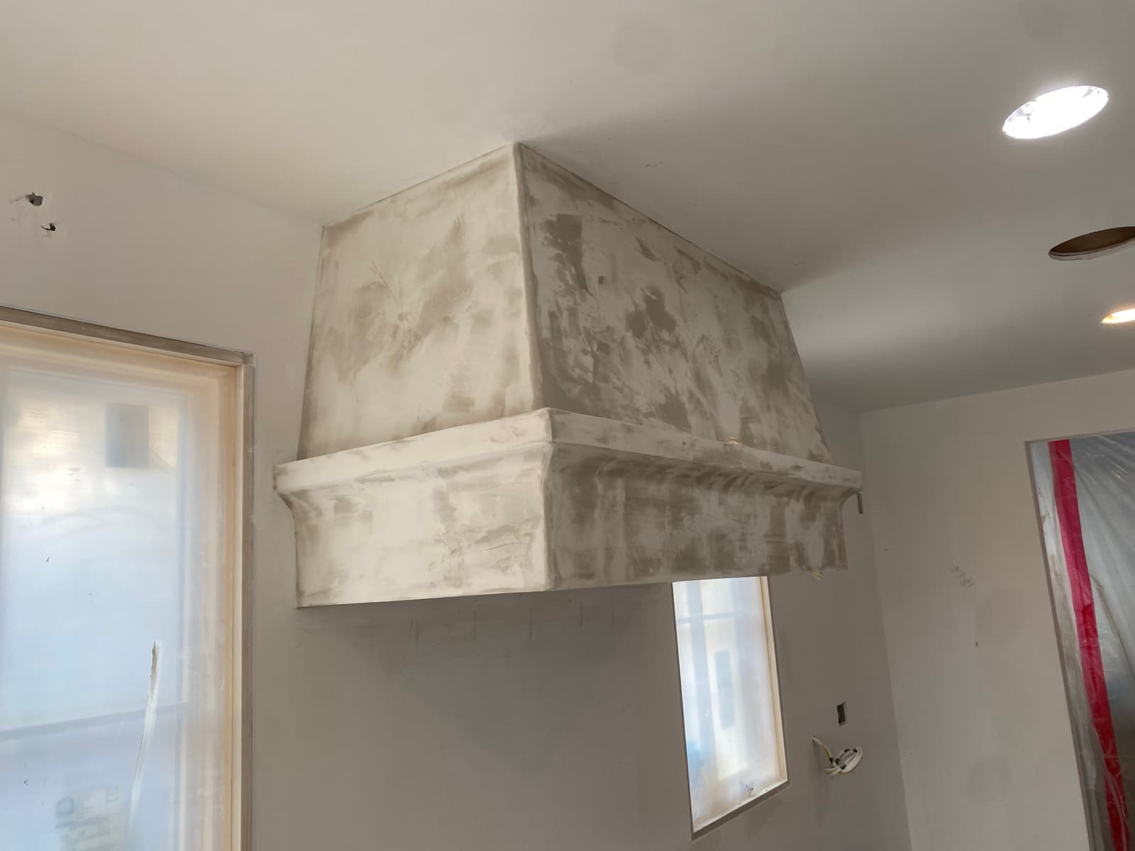 Custom white plaster range hood with windows